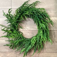 a close up of a green wreath on a wooden floor with wood planks in the background