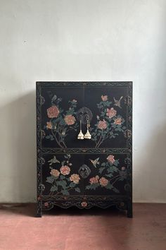 a black cabinet with flowers painted on it