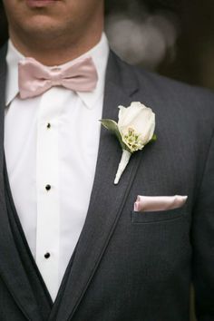 a man in a tuxedo with a pink bow tie and flower on his lapel