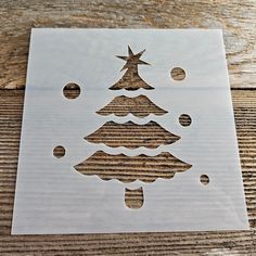 a cutout of a christmas tree on a wooden surface with circles and stars around it