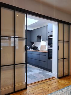 an open door leading to a kitchen with wooden floors and gray cabinetry on the walls