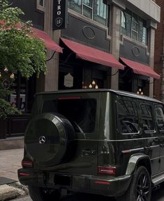 a mercedes g - class is parked on the side of the road in front of a building