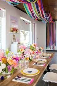 a long table with plates and flowers on it is set for a party or celebration