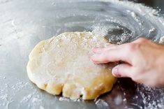 a person is kneading dough into a metal pan