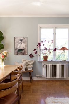 a dining room table and chairs with flowers in vases next to the radiator