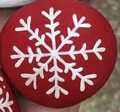 two red and white snowflake ornaments are on someone's hand, one is holding the other