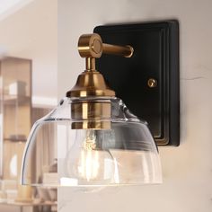 a wall light with a glass shade on the front and back of it's arm