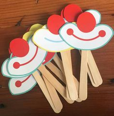 four popsicles with red and white toppings on top of wooden sticks in the shape of clown faces