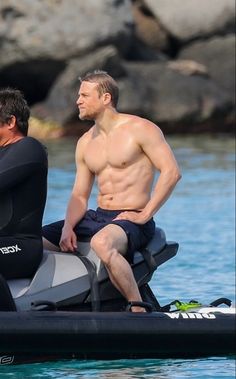 two men on a jet ski in the water with one man wearing a wet suit