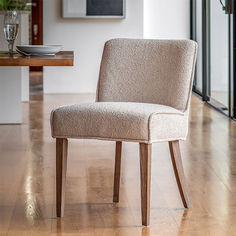 a beige chair sitting on top of a hard wood floor next to a wooden table