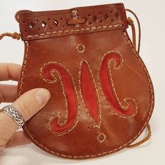 a hand holding a small brown purse with the letter j on it's side