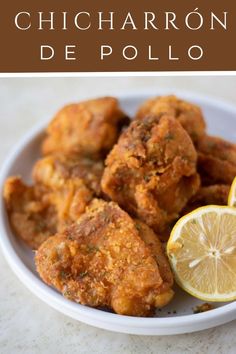 fried chicken is served in a bowl with lemon wedges