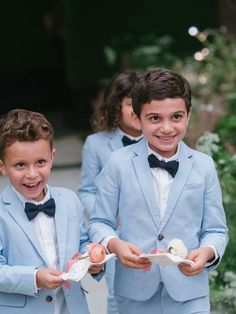 two young boys dressed in blue suits and bow ties holding small plates with food on them