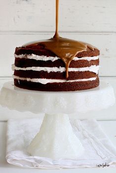 a chocolate cake with white frosting and caramel drizzle on top