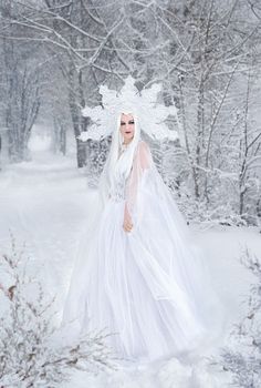 a woman dressed in white walking through the snow