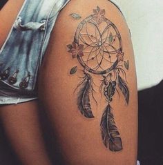 a woman's thigh with a tattoo that has a dream catcher and flowers on it