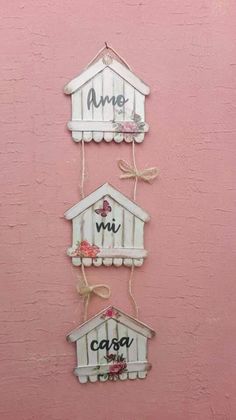 three wooden signs hanging on the side of a pink wall