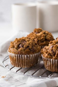 three muffins on a cooling rack next to a cup of coffee