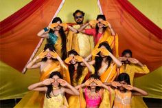 a group of people standing next to each other in front of a red and yellow curtain