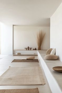 there are many rugs on the floor in this living room with white walls and floors