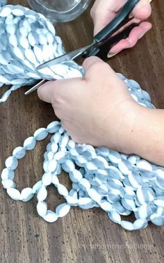 a person cutting chains with scissors on top of a wooden table covered in plastic beads