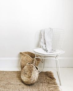 a white chair sitting on top of a floor next to a rug and a basket