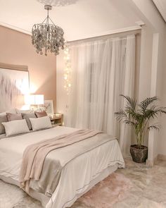 a bedroom with a bed, chandelier and two plants in the middle of the room