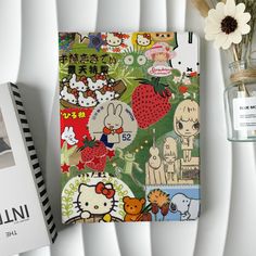 a hello kitty notebook sitting on top of a table next to a vase with flowers