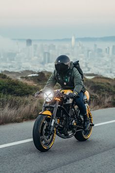 a person riding a motorcycle on the road in front of a large cityscape