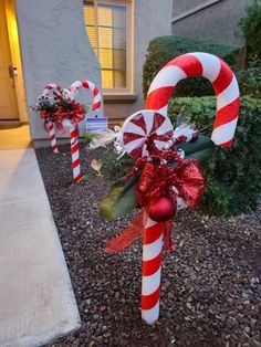 some candy canes are sitting on the ground in front of a house with red and white decorations