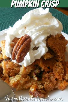 a close up of a piece of cake on a plate with whipped cream and pecans