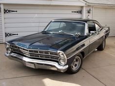 an old black car parked in front of a garage