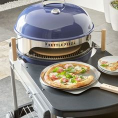 a pizza sitting on top of a plate next to a bbq with an open lid