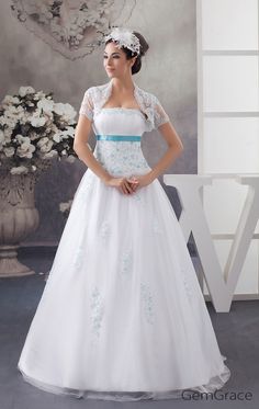 a woman in a white wedding dress standing next to a vase with flowers on it