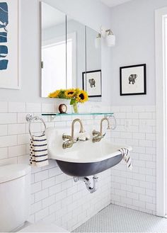 a bathroom with a sink, mirror and pictures on the wall above it's toilet