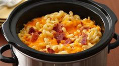 a crock pot filled with macaroni and cheese on top of a wooden table