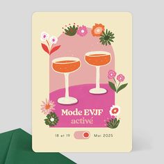 a card with two wine glasses on it next to a green envelope and some flowers