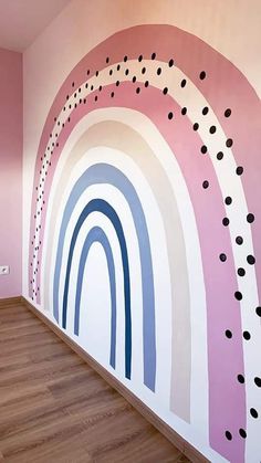 a room with pink walls and black polka dots on the rainbow painted wall, along with wood flooring