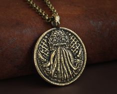 an old coin is sitting on top of a leather surface, with a chain attached to it