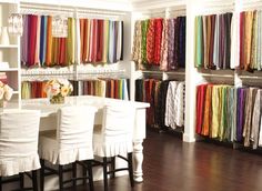 a room filled with lots of white chairs and colorful fabrics on the wall behind them