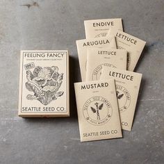 five seed packets sitting on top of a cement floor next to an envelope with the words lettuce and seattle seed co