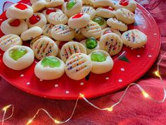 a red plate topped with cookies covered in frosting and sprinkles on top of a table