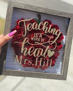 a person holding up a paper cutout with the words teaching is a work of heart