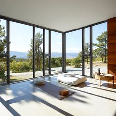 an empty room with large windows and a bed on the floor in front of it