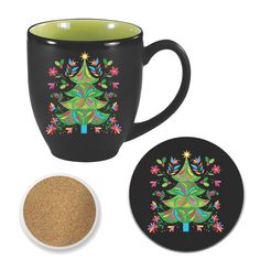 a coffee cup with a christmas tree on it next to a coaster and cork coaster