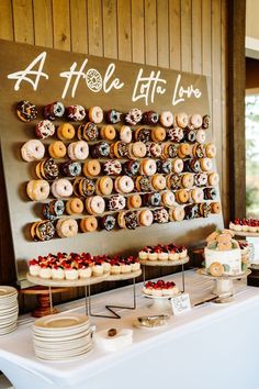 a table topped with lots of donuts on top of plates and cups next to a sign