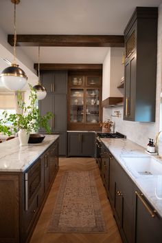 a kitchen with wooden cabinets and marble counter tops, along with an area rug on the floor