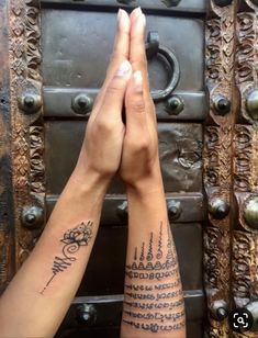 two people holding hands in front of an ornate door with writing on their arm and wrist