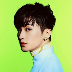 a young man with black hair wearing a white turtle neck shirt and gold hoop earrings