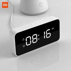 an alarm clock sitting on top of a table next to a white object with the time displayed